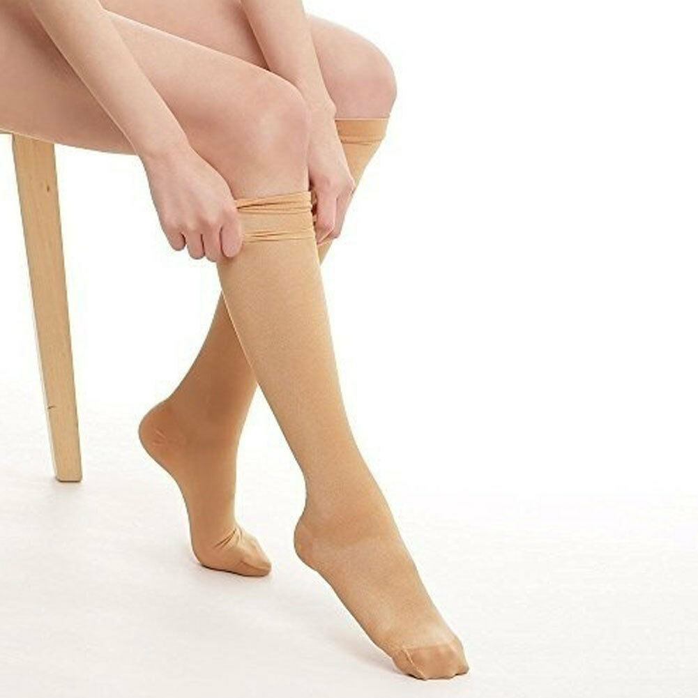 Person wearing beige knee-high socks on a white background