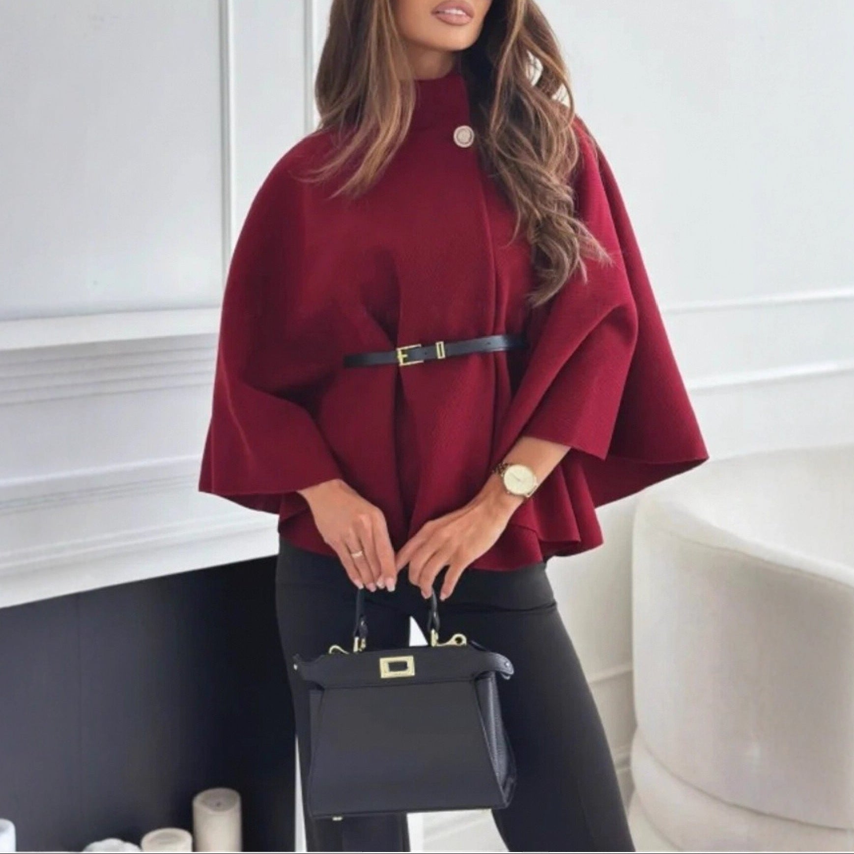 Woman wearing a red cape with a black handbag indoors