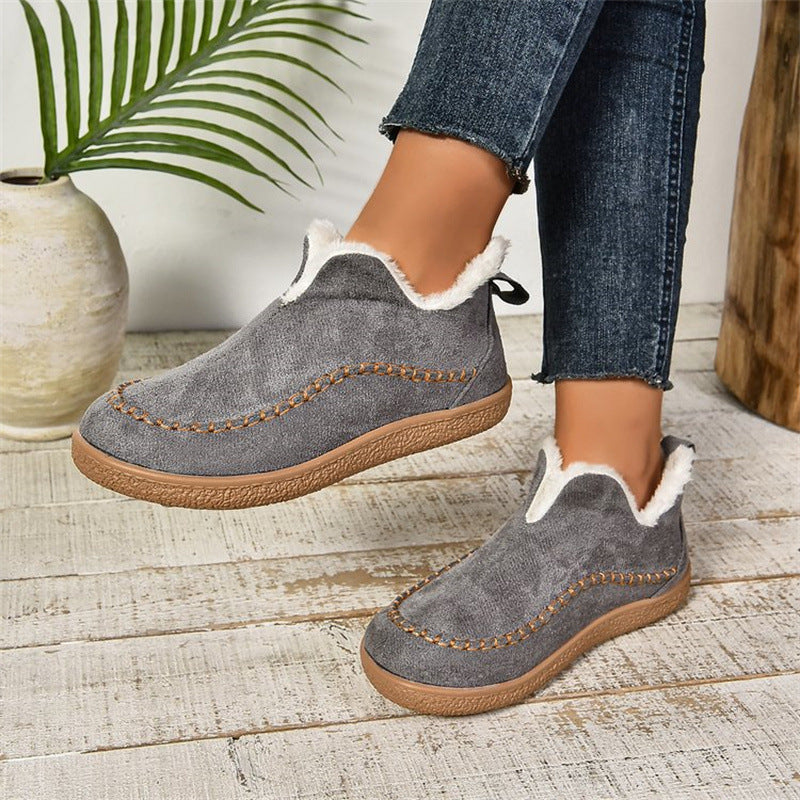 Gray slip-on shoes with white fur lining worn indoors on a wooden floor.