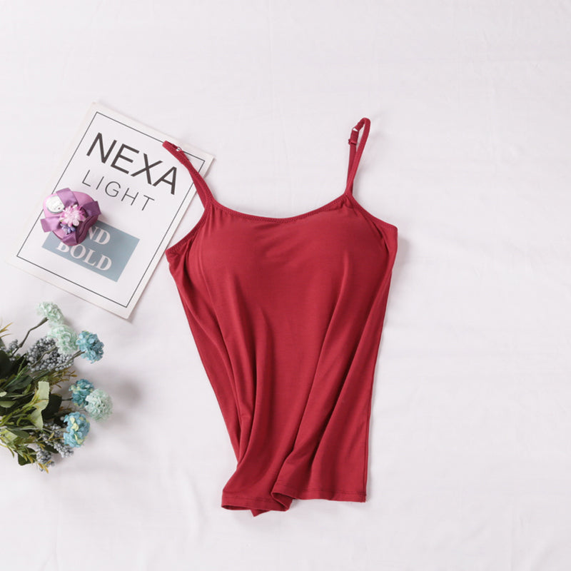 Red spaghetti strap top on a white background with a magazine and flowers.