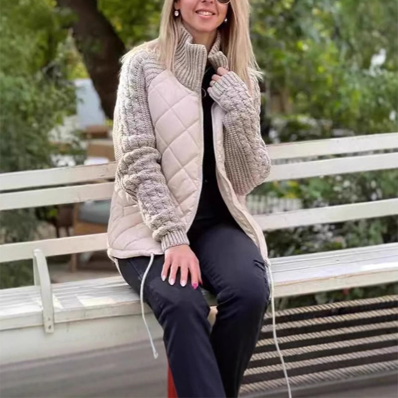 Woman wearing a beige quilted jacket sitting on a bench outdoors.