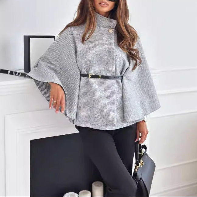 Woman wearing a gray poncho and sunglasses in an indoor setting