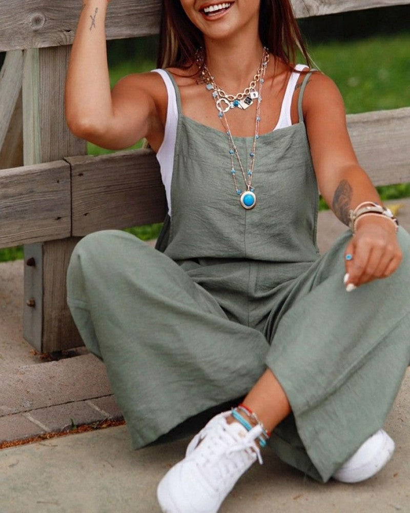 Woman wearing a green jumpsuit sitting on a wooden bench.