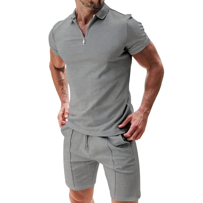 Man wearing a gray checkered polo shirt and shorts on a white background