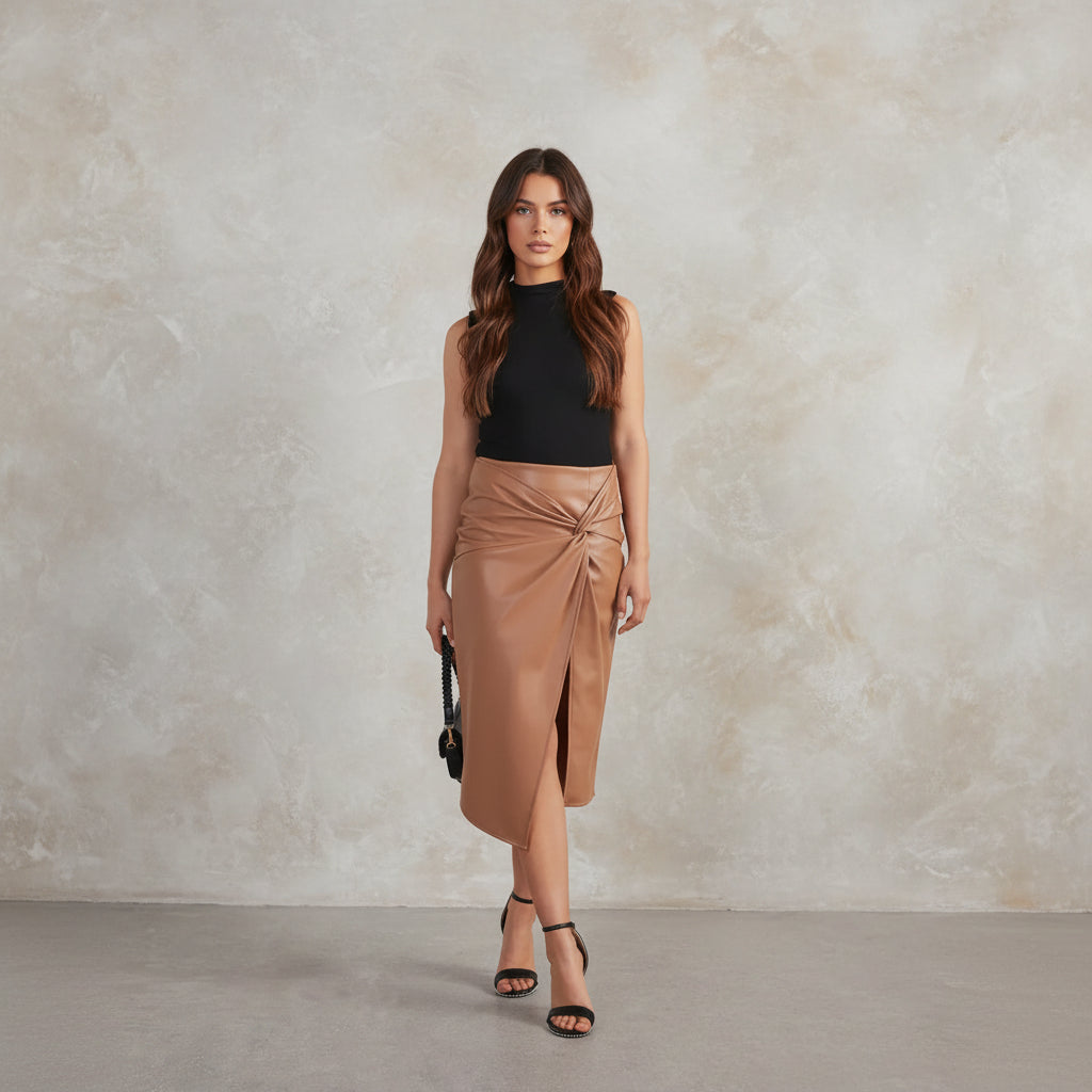 Woman wearing a black sleeveless top and tan wrap skirt against a white background