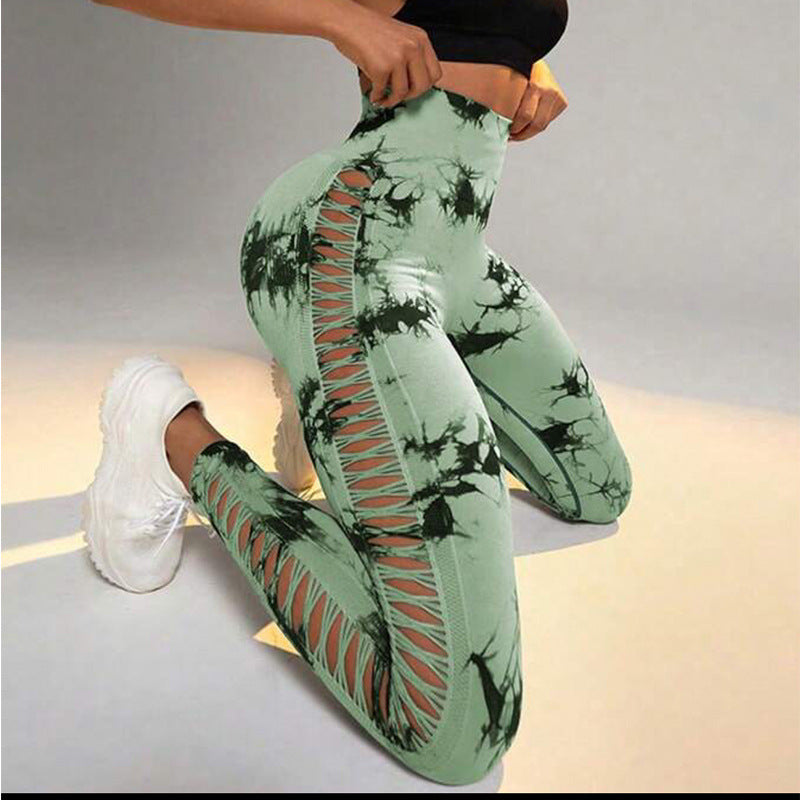 Green tie-dye leggings with black patterns worn by a person sitting on a light-colored surface.