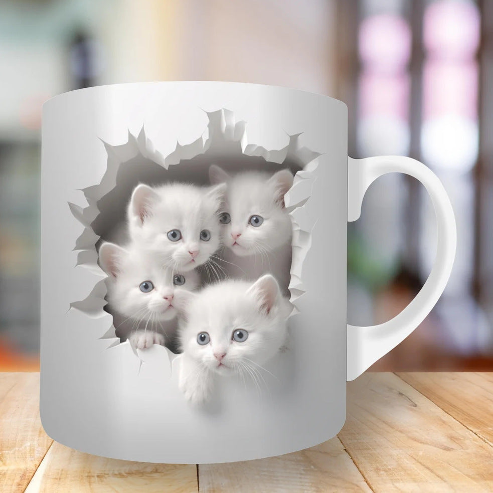 White mug with cut-out design of three white kittens on a wooden surface.