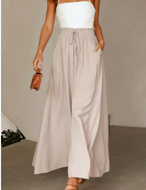 Woman wearing a white top and beige wide-leg pants against a neutral background