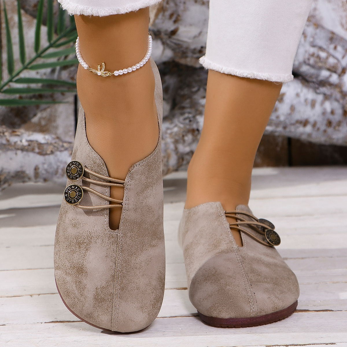 Beige suede shoes worn by a person on a wooden floor with a blurred background