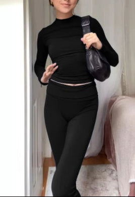 Person wearing a black outfit with a black bag in a room.