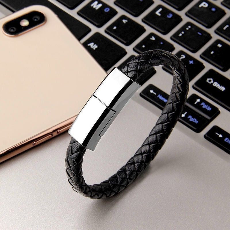 Black braided leather bracelet with metal clasp on a laptop keyboard