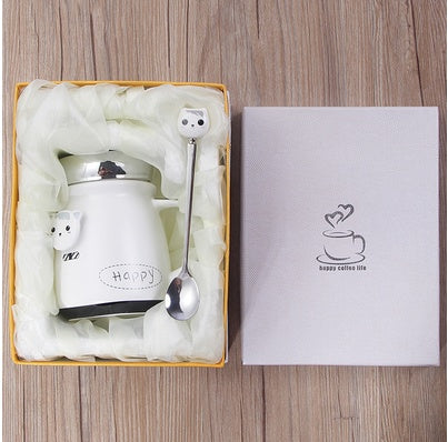 White ceramic mug with lid, spoon, and decorative box on a wooden surface