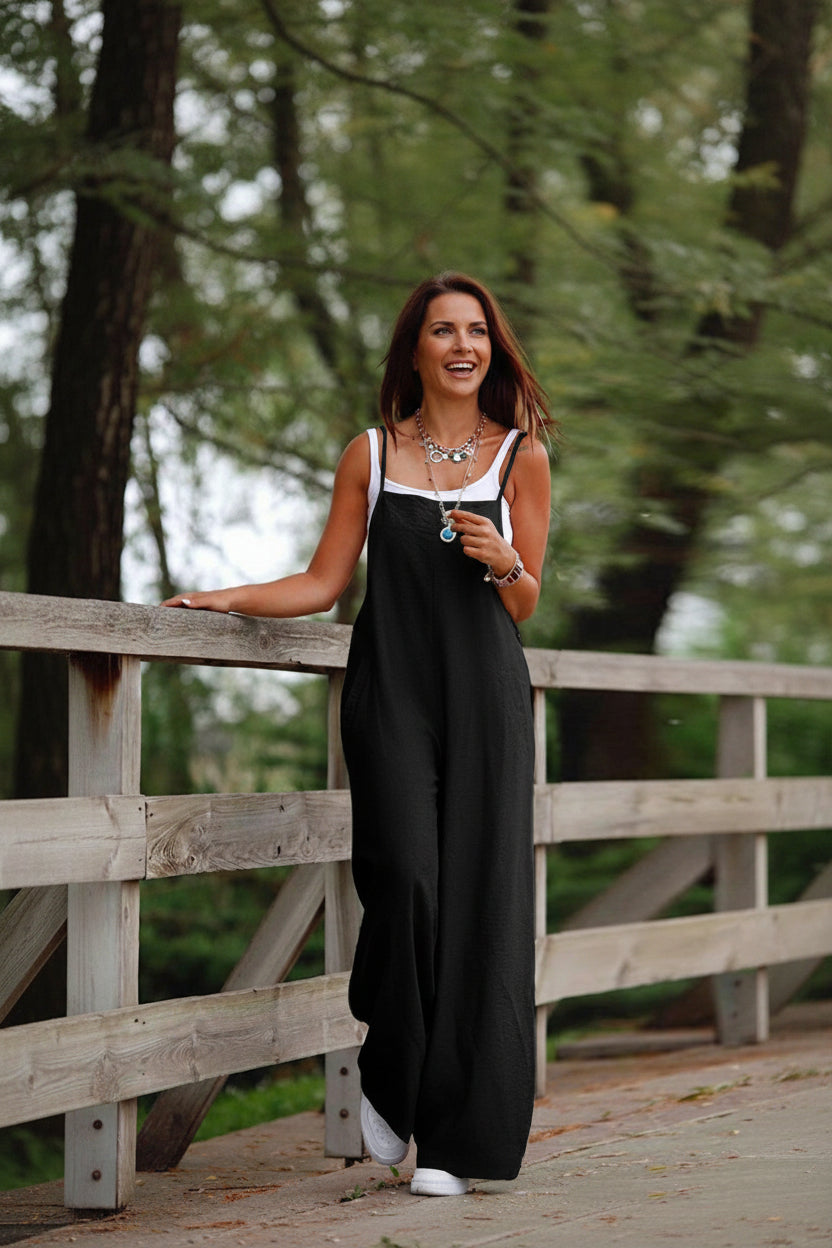 Woman wearing a black dress standing by a wooden fence outdoors