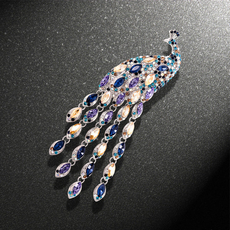 Jewelry brooch shaped like a peacock feather with multicolored stones on a dark background