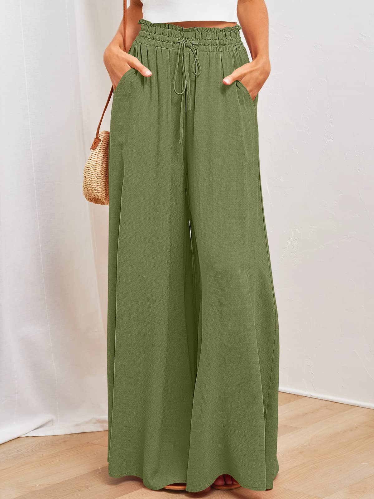 Person wearing green wide-leg pants with a white background
