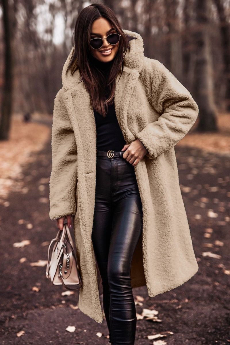 Woman wearing a long beige coat in a forest setting