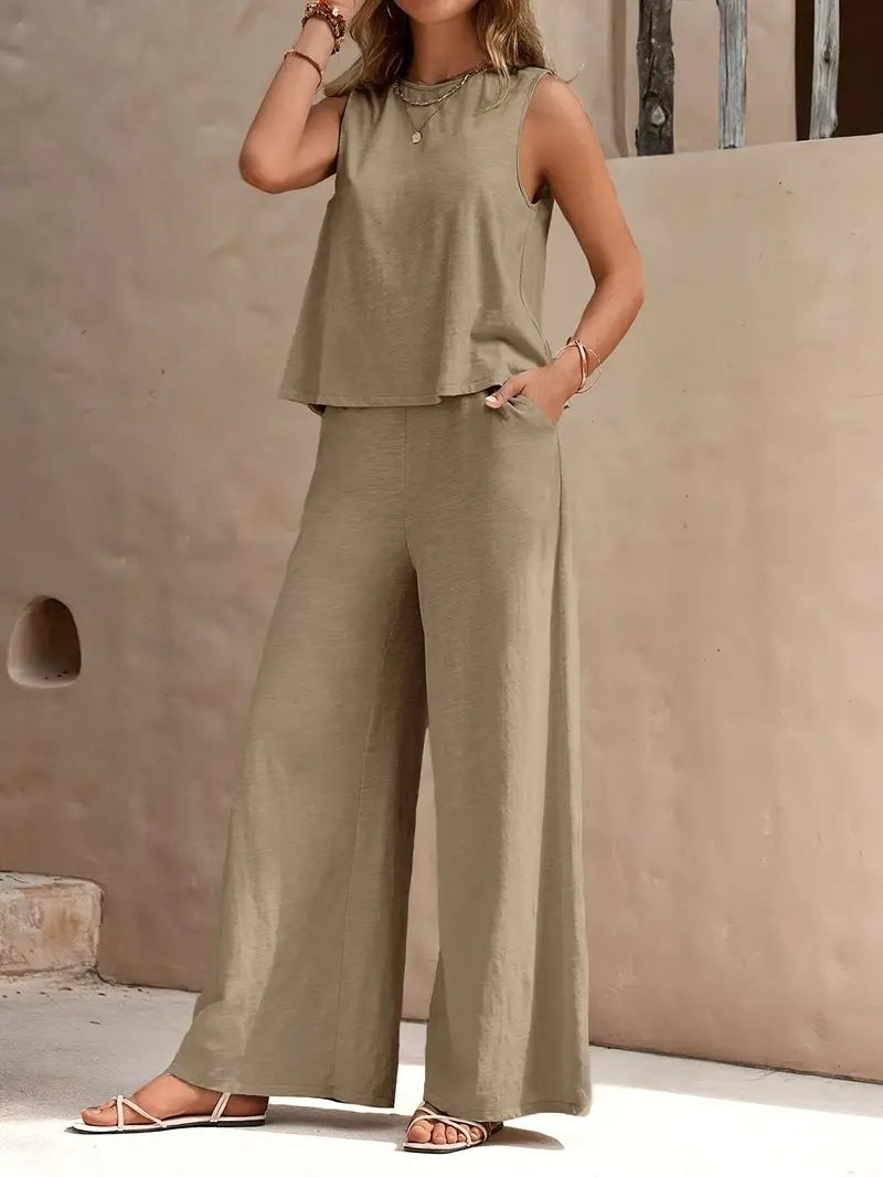 Woman wearing a green sleeveless top and wide-leg pants against a beige wall.