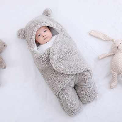 Baby wrapped in a fluffy gray bear costume on a white background