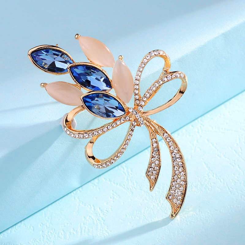 Decorative brooch with blue gemstones and gold accents on a light blue background