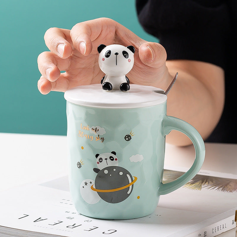 Mint green mug with panda design and panda-shaped tea infuser held by a hand.