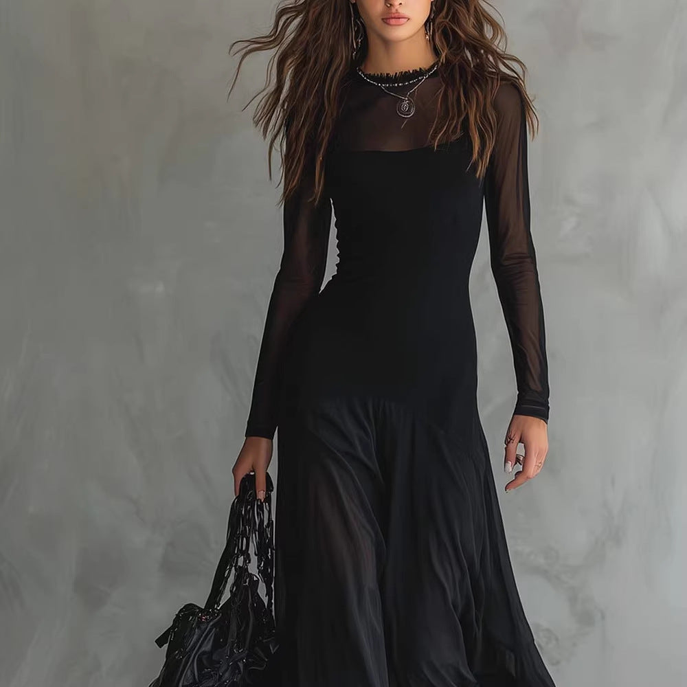 Person wearing a long black dress with sheer sleeves against a gray background