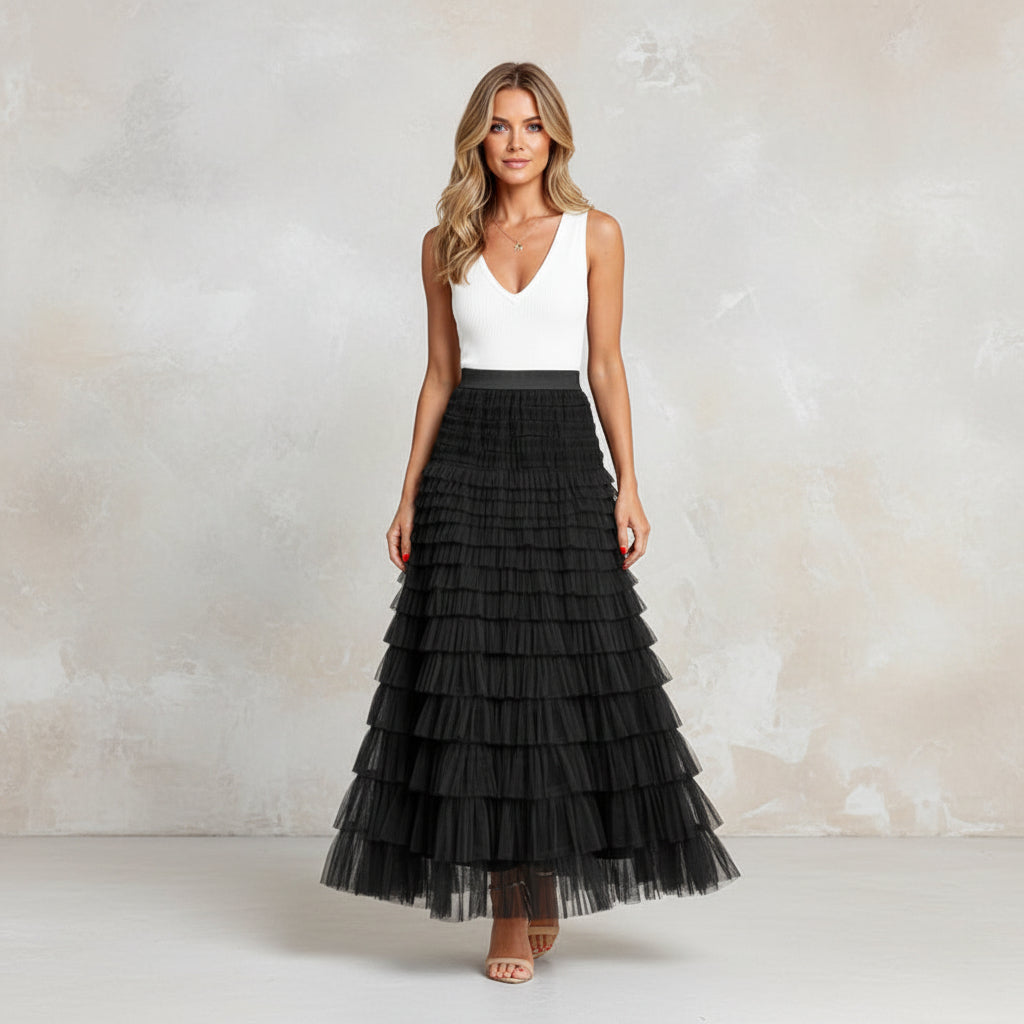 Woman wearing a white top and black tiered skirt standing on stone steps.
