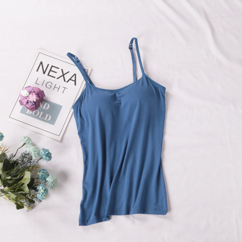 Blue camisole on a white surface with a magazine and flowers.