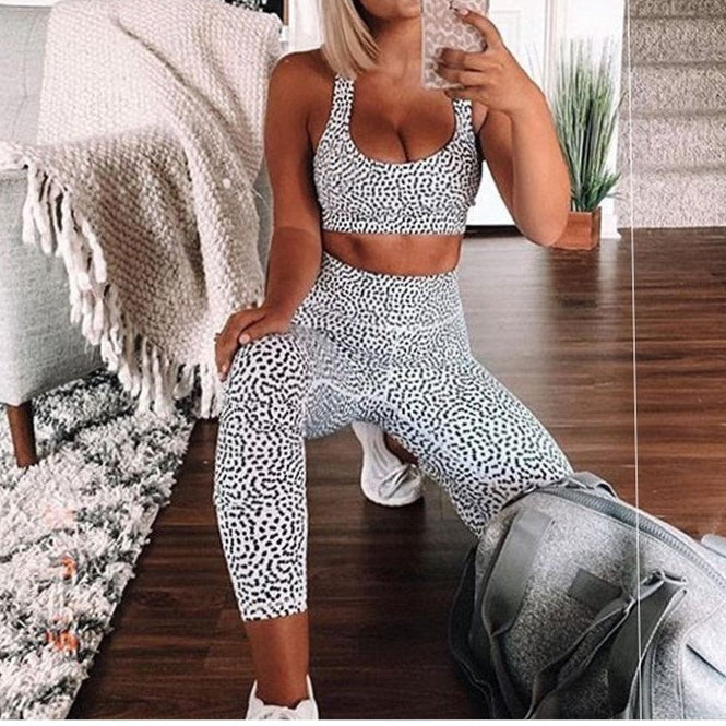 Woman taking a mirror selfie wearing a black and white patterned outfit in a home setting.