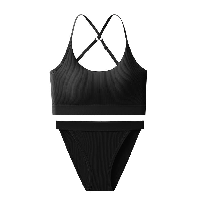 A two-piece black ribbed bikini set featuring a sports bra top with crisscross back straps and matching high-cut bottoms, shown flat on a white background.
