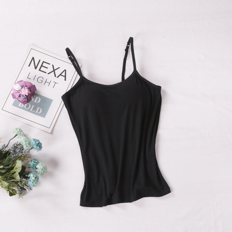 Black spaghetti strap top on a white background with a magazine and flowers.