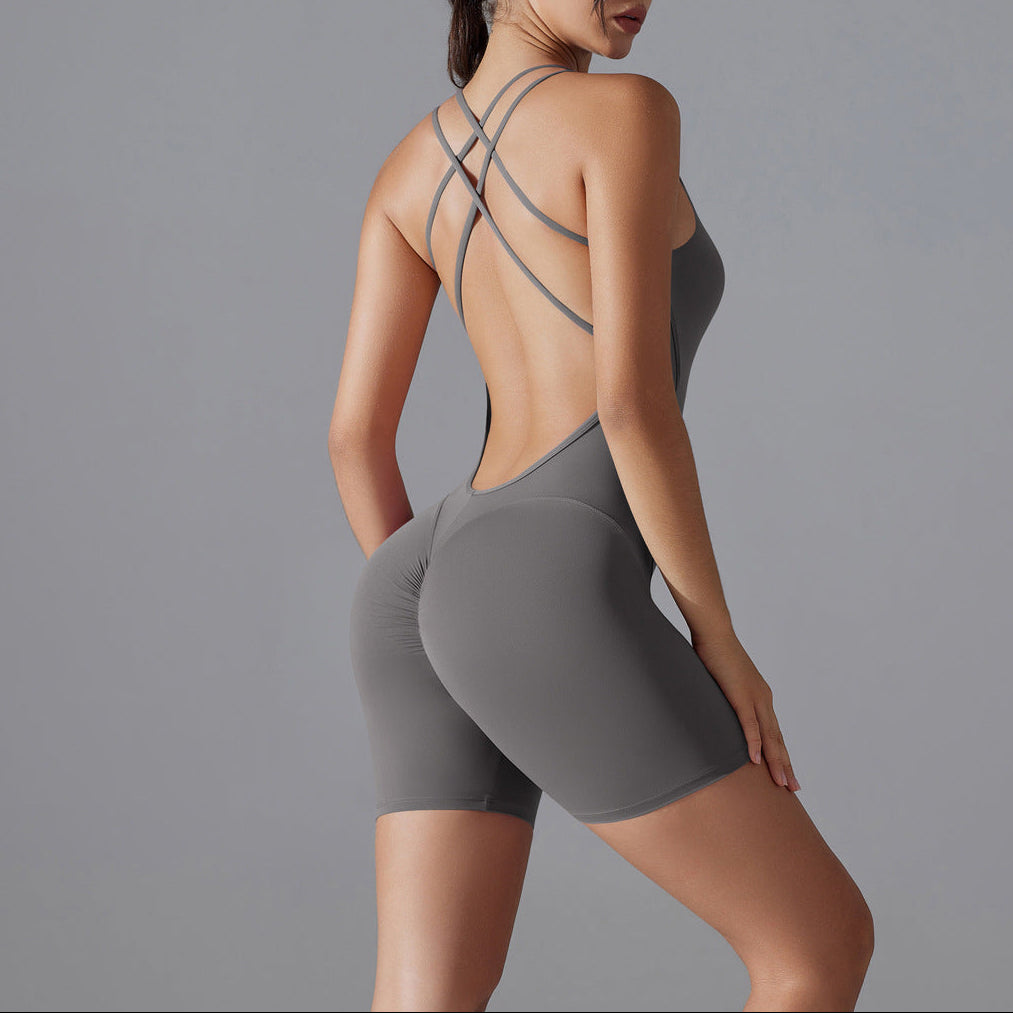Woman wearing a gray athletic outfit with criss-cross straps on a gray background