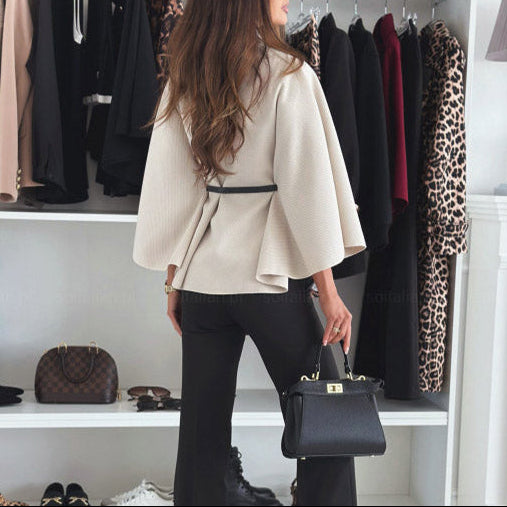 Woman in a stylish outfit standing in a well-organized clothing store with various garments and accessories.