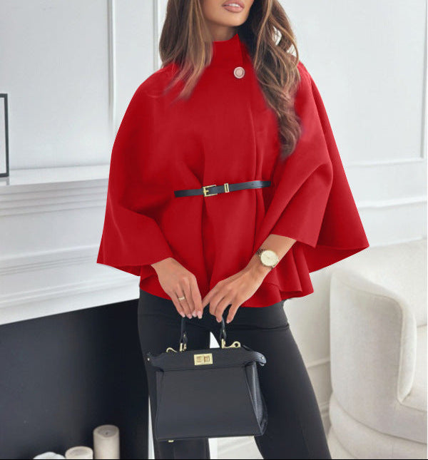 Woman wearing a red cape and holding a black handbag indoors.