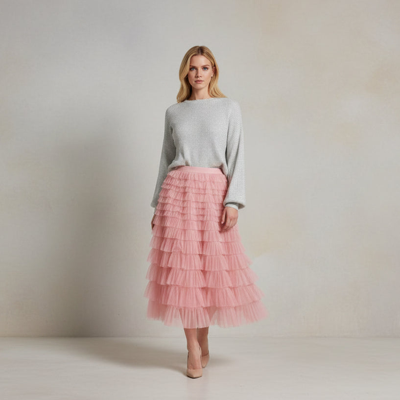 Person wearing a pink ruffled skirt and holding a brown handbag indoors.