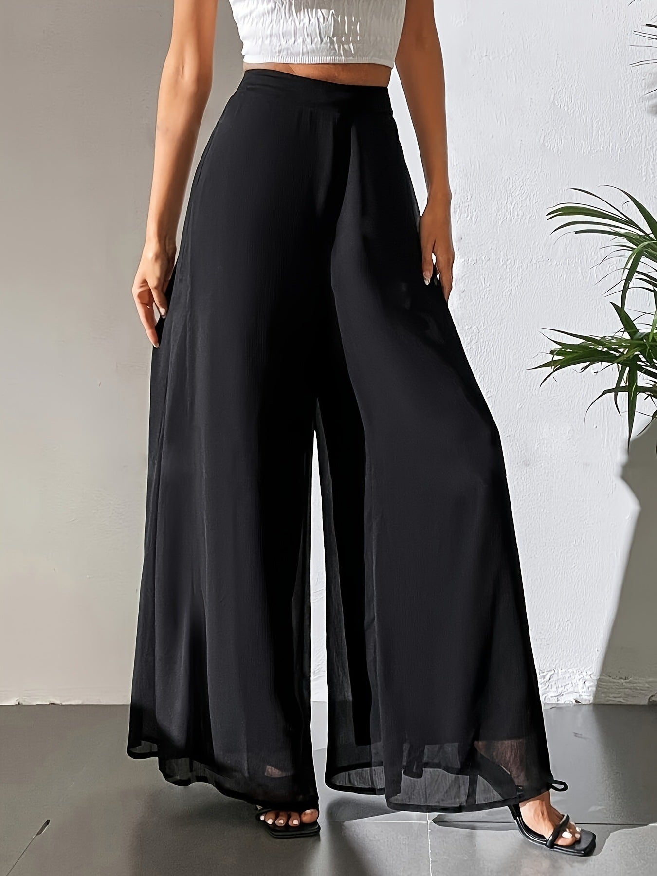 Person wearing black wide-leg pants against a neutral background