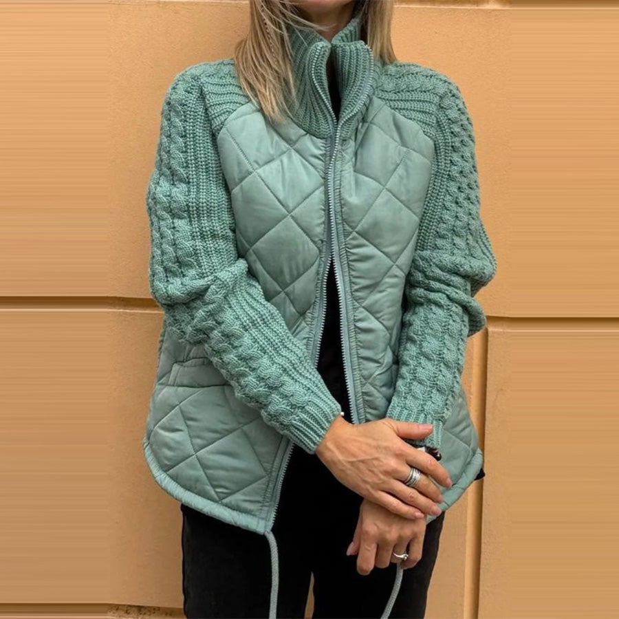 Person wearing a teal quilted jacket against a beige wall