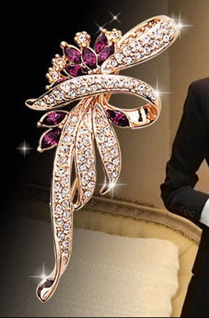 Woman in formal attire wearing a decorative brooch with a close-up of the brooch on a dark background.