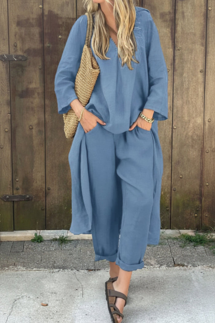 Woman wearing a blue outfit with a straw bag against a wooden wall.