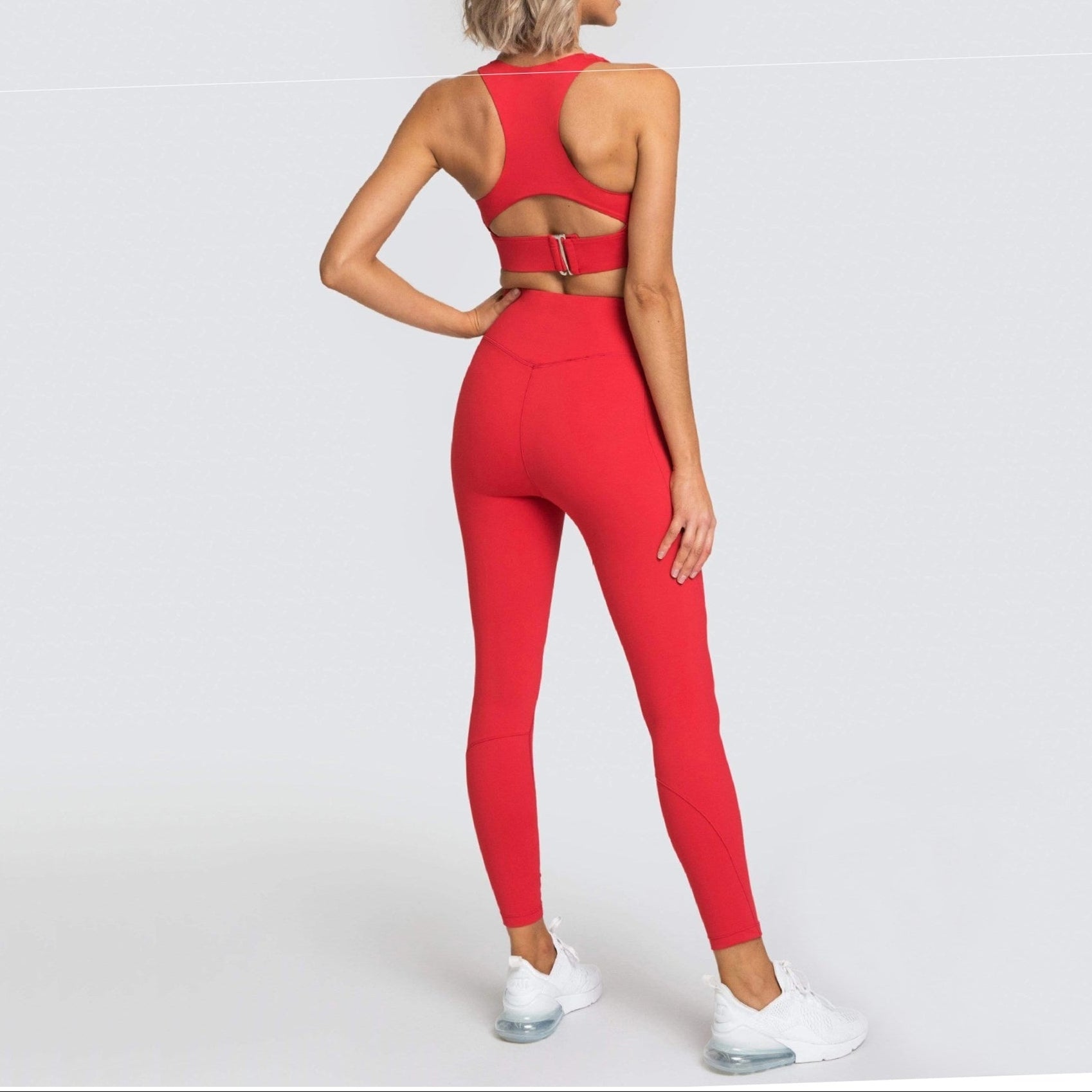 Woman wearing a red sports bra and leggings set on a white background