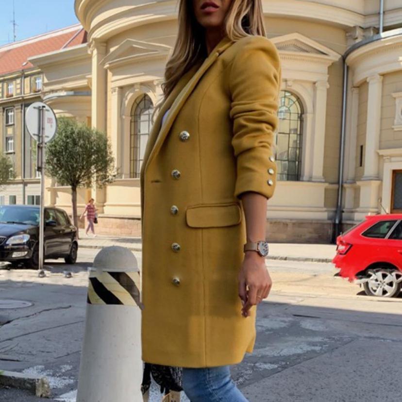 Person wearing a yellow coat on a city street with buildings and cars in the background
