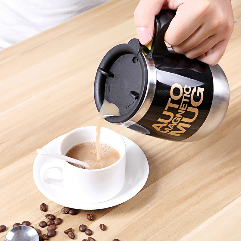 Person pouring coffee from an Auto Magnetic Mug into a white cup on a wooden surface.