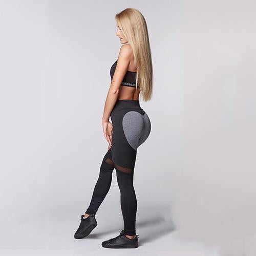 Woman wearing black leggings with a gray heart design on a plain background