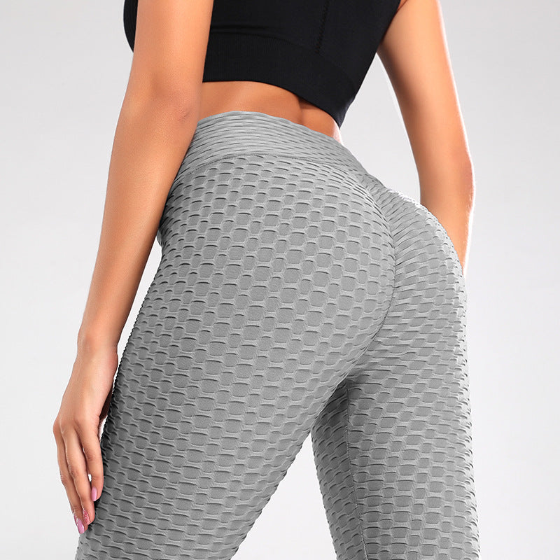 Person wearing gray textured leggings on a plain background