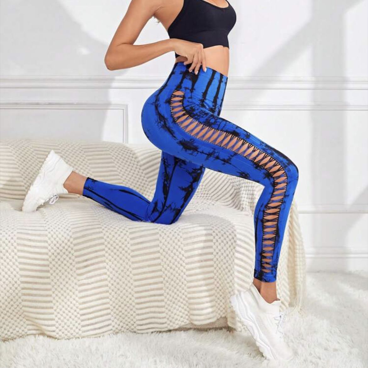 Person wearing blue leggings with mesh panels sitting on a bed.