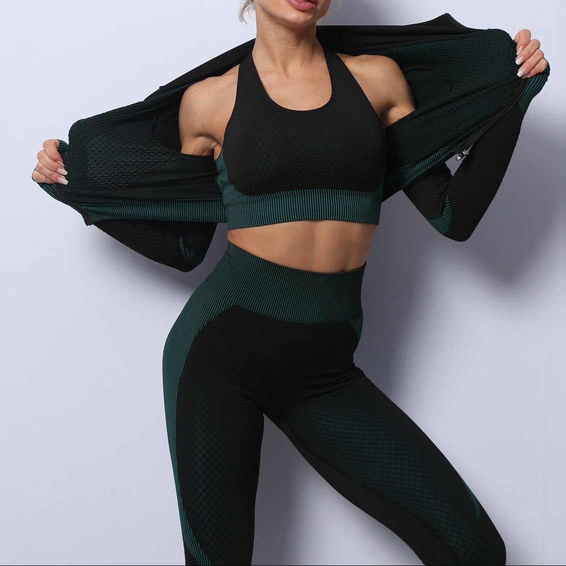 Woman in black and green athletic wear posing against a light gray background