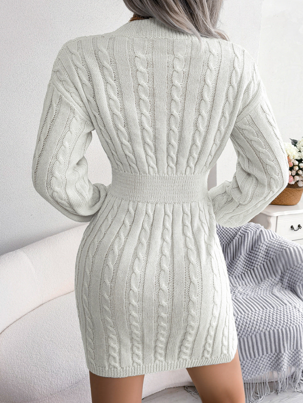 Person wearing a light gray cable knit dress with long sleeves in a casual setting.