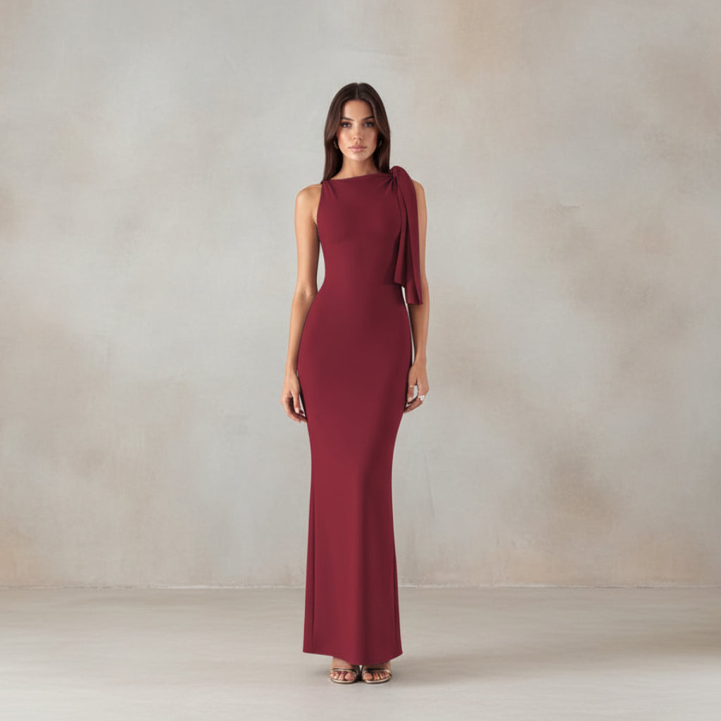 Woman in a burgundy evening gown standing on marble steps.