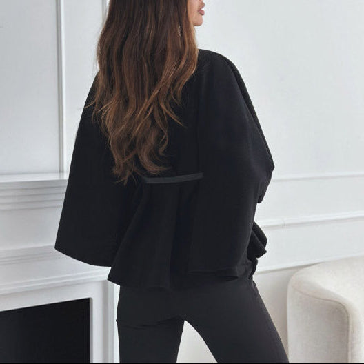 Woman wearing a black outfit in a minimalistic room.