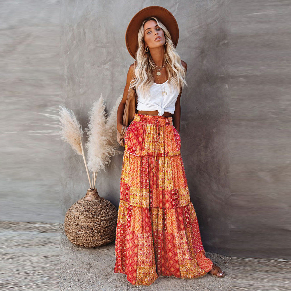 Woman wearing a bohemian outfit with a hat, white top, and colorful skirt against a neutral background.