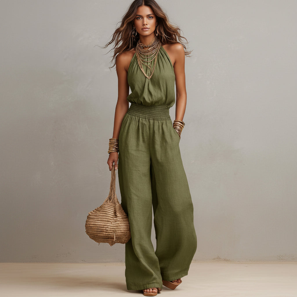 Woman wearing a green jumpsuit holding a woven bag against a neutral background